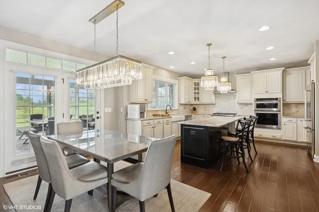 a kitchen with stainless steel appliances granite countertop a sink dishwasher a stove a refrigerator with a dining table and chairs