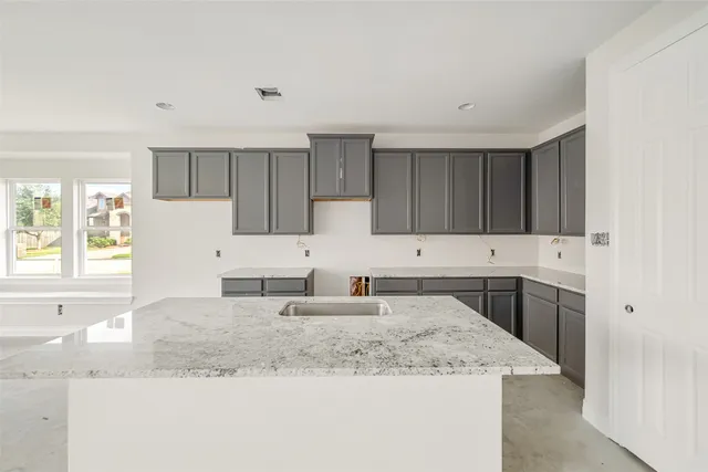 a kitchen with granite countertop a sink stove and cabinets