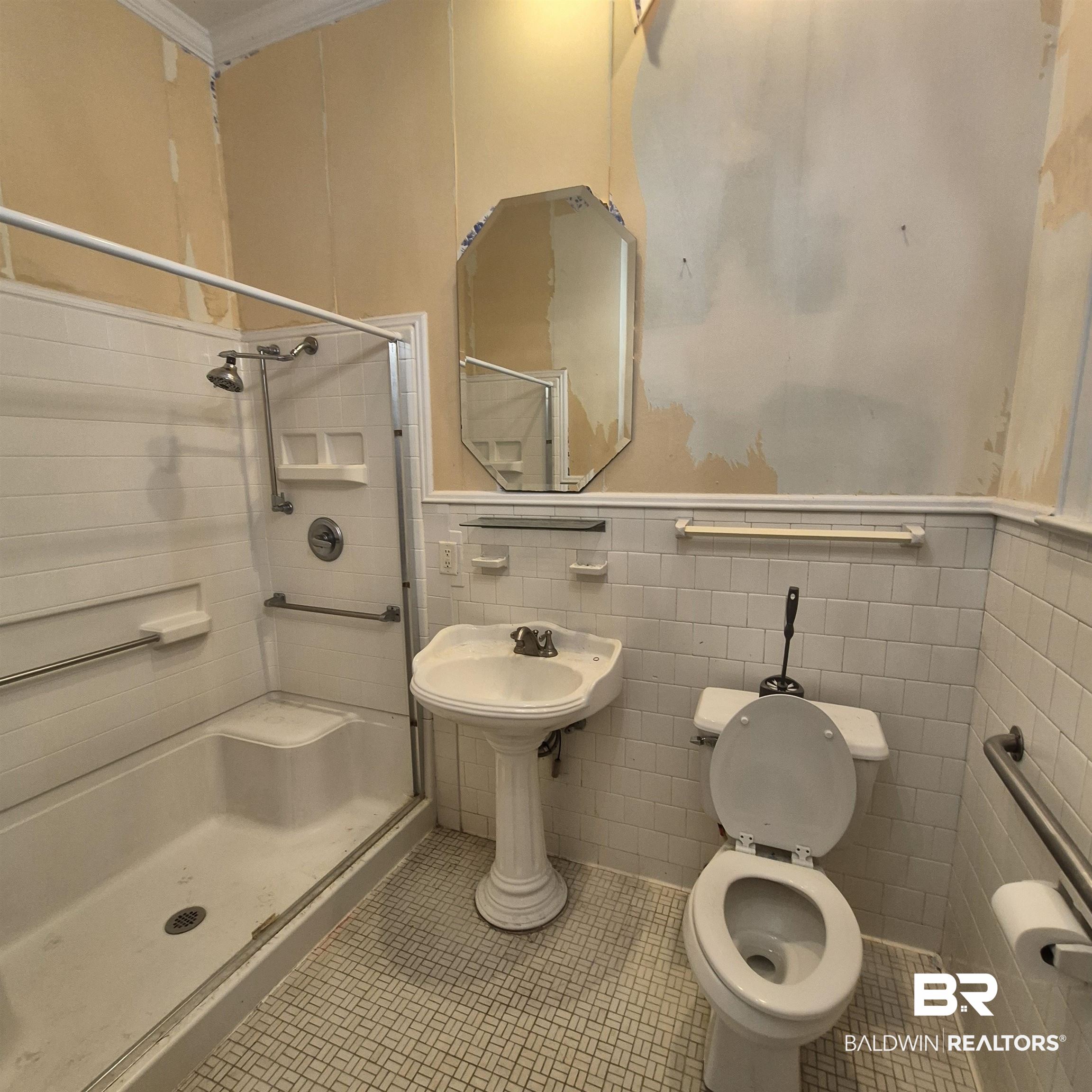 308 Rural Street Evergreen, AL 36401 - Photo 26 of 40 Full bath featuring tile walls, wainscoting, a shower stall, and tile patterned floors