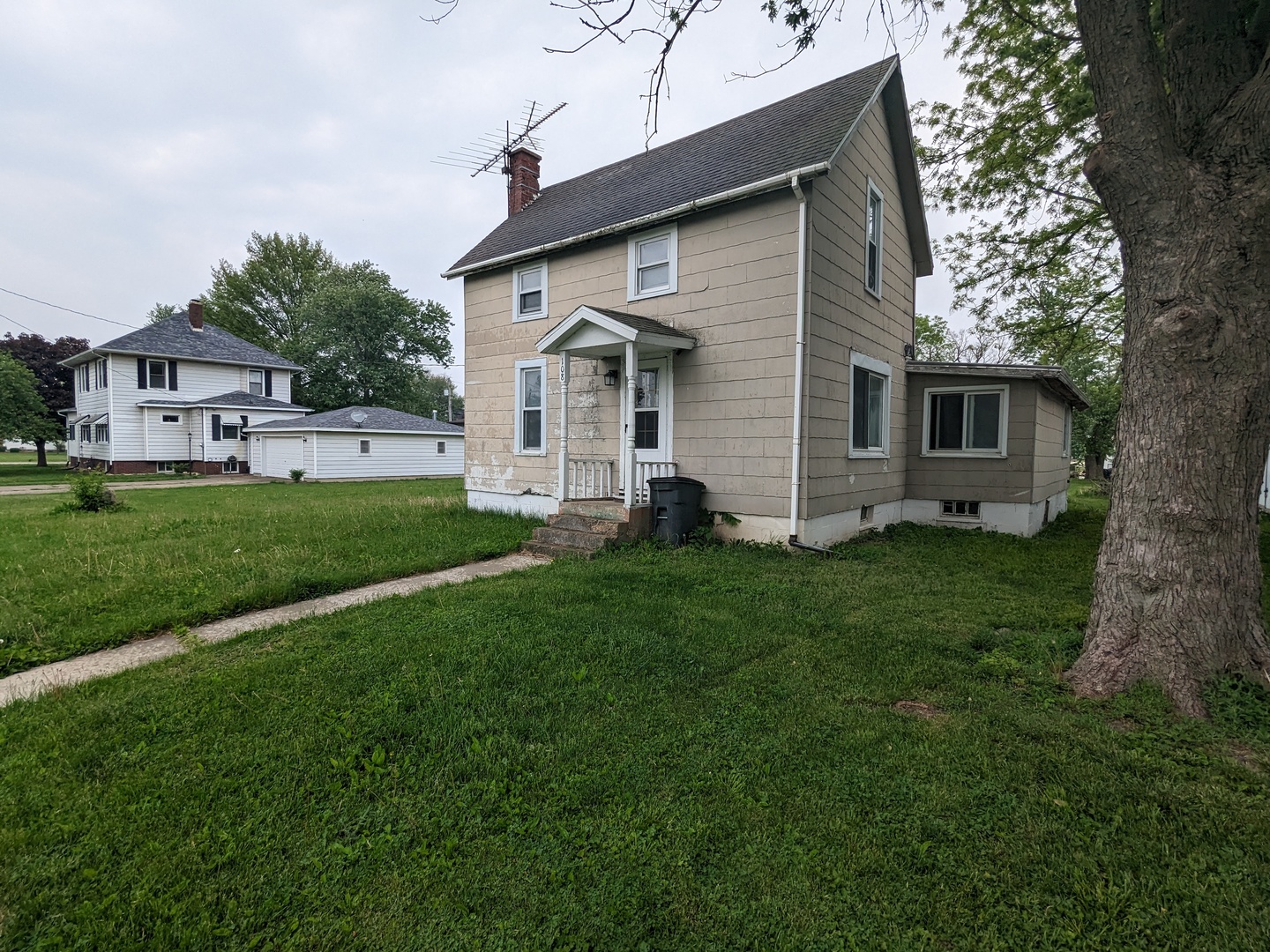 a view of a house with a big yard potted plants and large tree