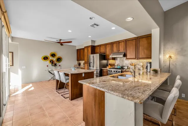a kitchen with granite countertop kitchen island stainless steel appliances a sink a stove top oven a counter space and cabinets