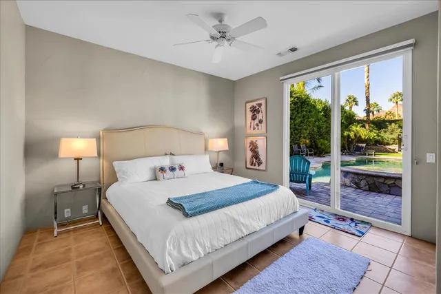 a bedroom with a large bed and a chandelier fan
