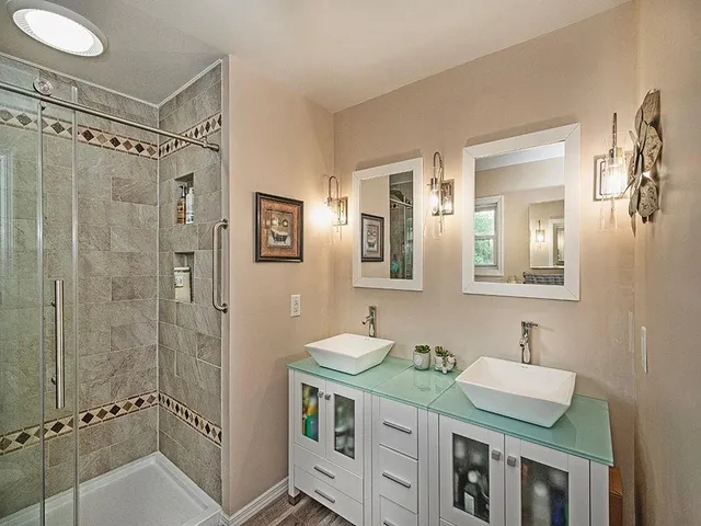 a bathroom with a double vanity sink mirror and shower