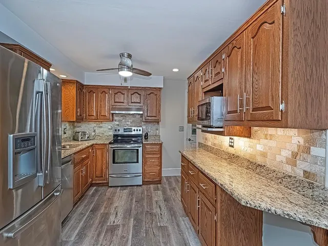 a kitchen with stainless steel appliances granite countertop a stove a sink dishwasher and a refrigerator