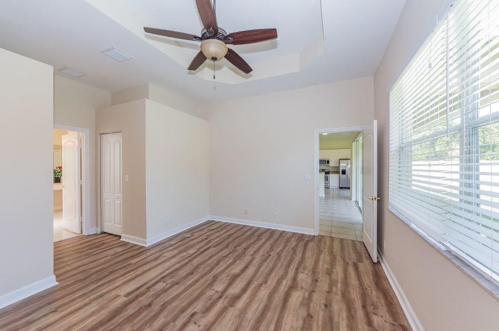 5825 Spanish River Road Fort Pierce, FL 34951 - Photo 13 of 36 a view of a room with wooden floor ceiling fan and windows