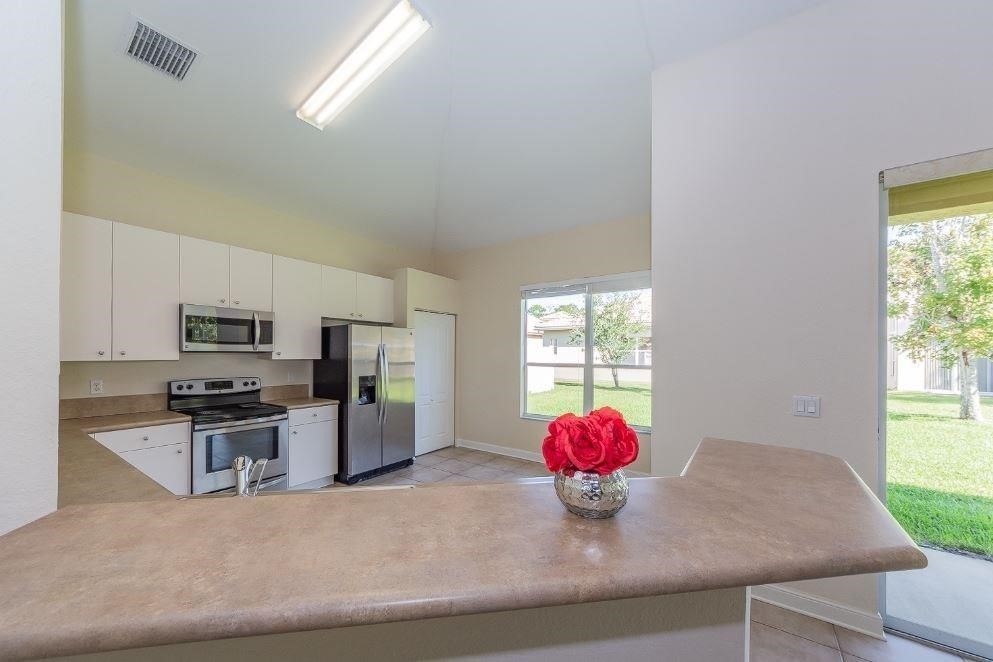 5825 Spanish River Road Fort Pierce, FL 34951 - Photo 7 of 36 a kitchen with granite countertop a sink cabinets stainless steel appliances and a window