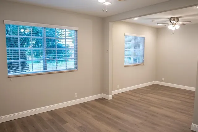 an empty room with wooden floor and windows
