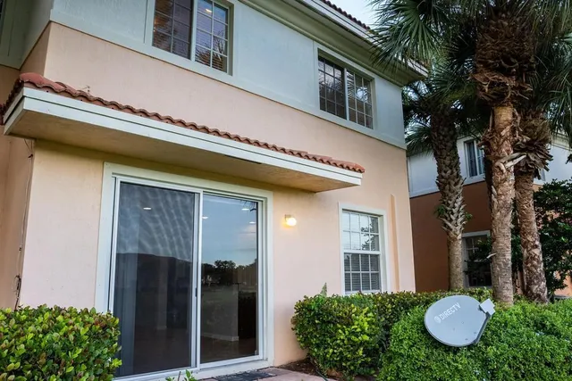 a view of a house with potted plants and a table and chairs