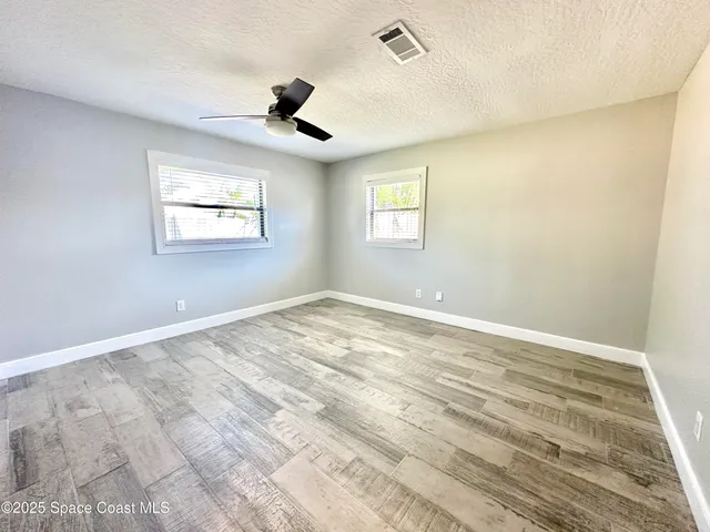 a view of empty room with wooden floor