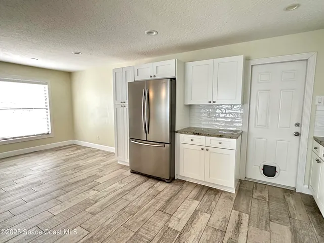 a kitchen with a refrigerator a stove top oven and white cabinets