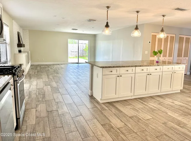 a view of a kitchen with kitchen island white cabinets and wooden floor