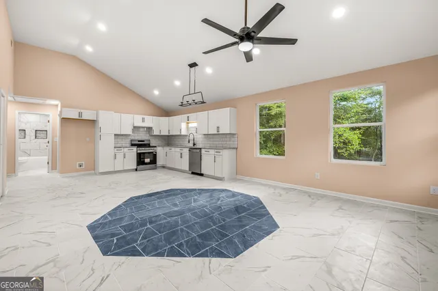 a view of an empty room with a kitchen and window