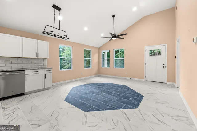 a kitchen with granite countertop a refrigerator a sink and white cabinets