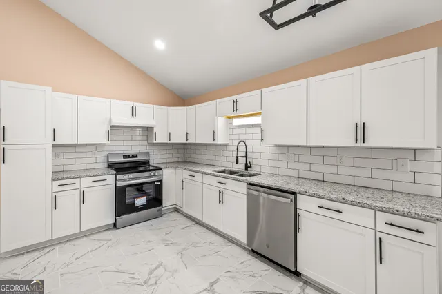 a large white kitchen with a stove a sink dishwasher and a refrigerator with wooden floor