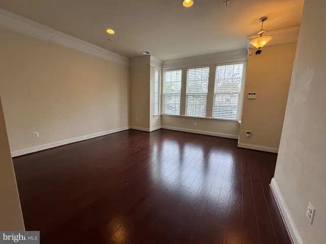 an empty room with wooden floor and windows with curtains