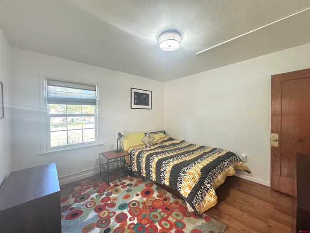 a bedroom with a bed and a lamp with wooden floor