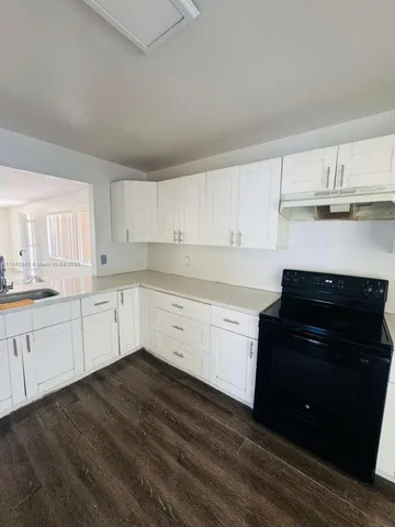 a view of a kitchen with granite countertop white cabinets and black appliances