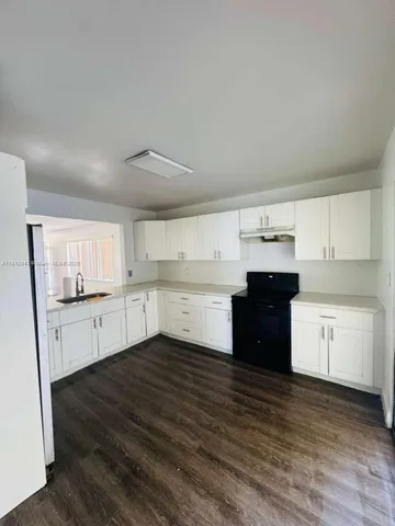a kitchen with granite countertop a refrigerator and cabinets