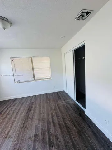an empty room with wooden floor cabinet and windows