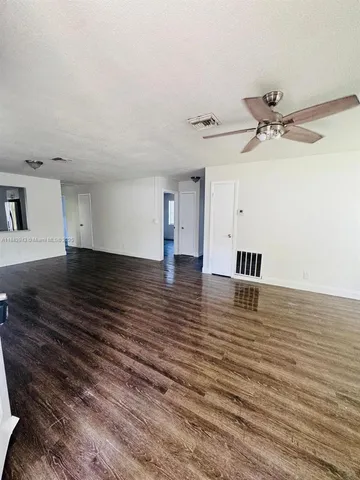a view of empty room with wooden floor and ceiling fan