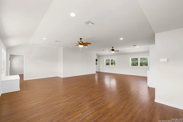 a view of an empty room with wooden floor and a window