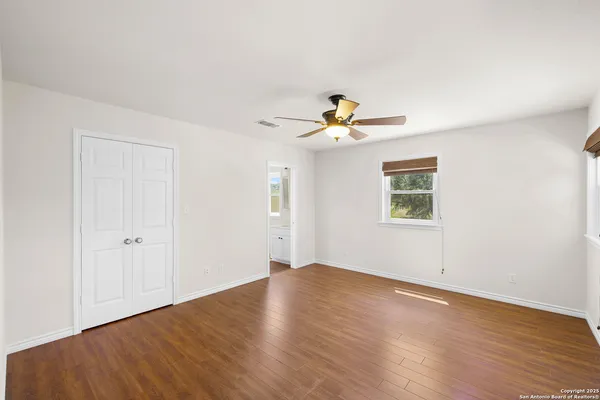 an empty room with wooden floor chandelier and windows