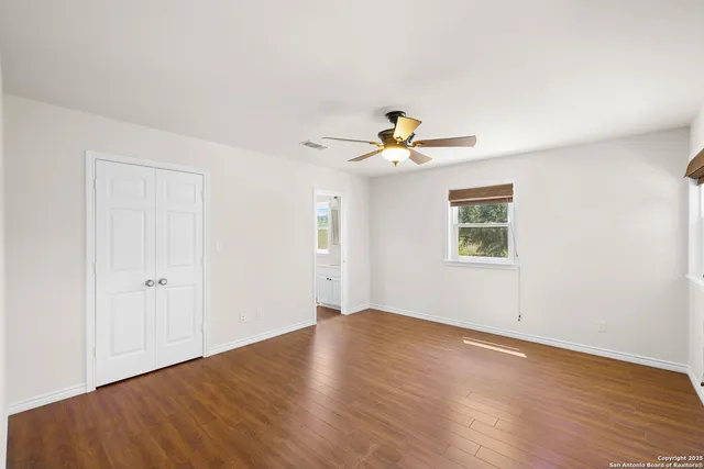 an empty room with wooden floor chandelier and windows