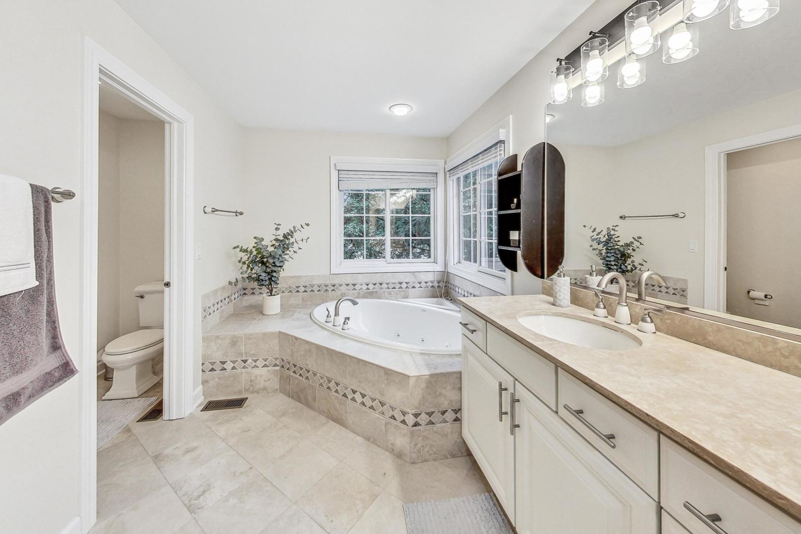2680 Summit Drive Glenview, IL 60025 - Photo 33 of 70 a spacious bathroom with a granite countertop double vanity sink a large mirror a bathtub and next to a window