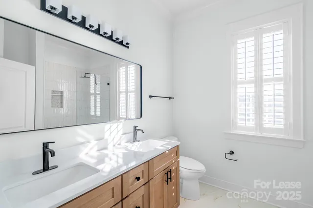 a bathroom with a granite countertop sink a toilet and a mirror