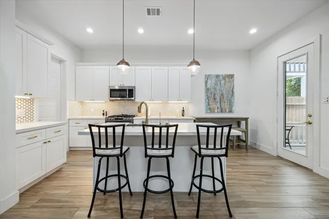 a kitchen with stainless steel appliances granite countertop a kitchen island a stove a kitchen island a dining table and chairs