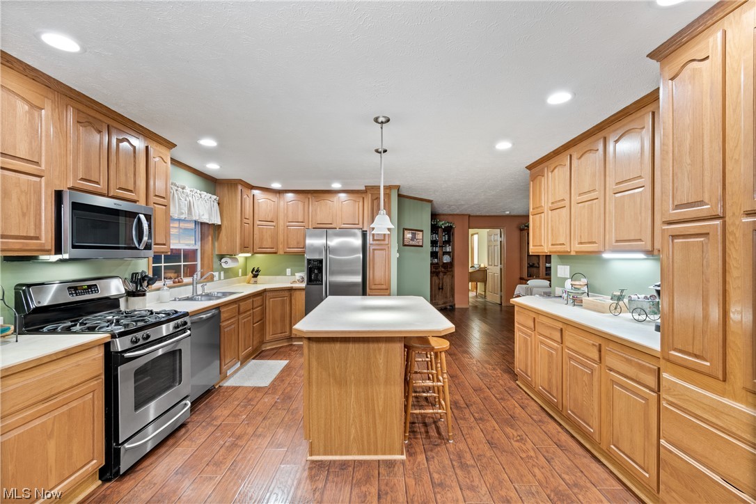 2240 Prysi Road Northwest Dover, OH 44622 - Photo 12 of 35 Kitchen featuring wood-type flooring, sink, a kitchen island, pendant lighting, and stainless steel appliances