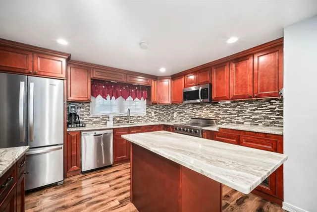 a kitchen with stainless steel appliances granite countertop a refrigerator a sink dishwasher a stove with wooden cabinets and floor