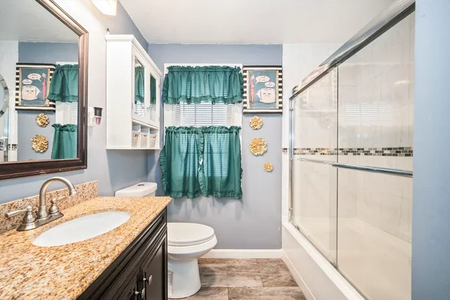a bathroom with a granite countertop sink toilet and shower