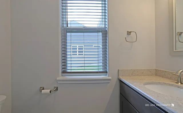 a bathroom with a granite countertop sink and a window