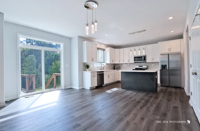 a kitchen with stainless steel appliances kitchen island wooden floors refrigerator and cabinets