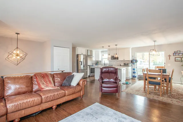a living room with furniture kitchen view and a chandelier