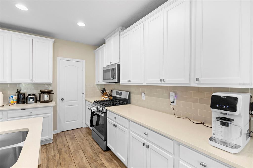 3937 Ceremony Cove Sanford, FL 32771 - Photo 6 of 51 a kitchen with a sink dishwasher stove and white cabinets