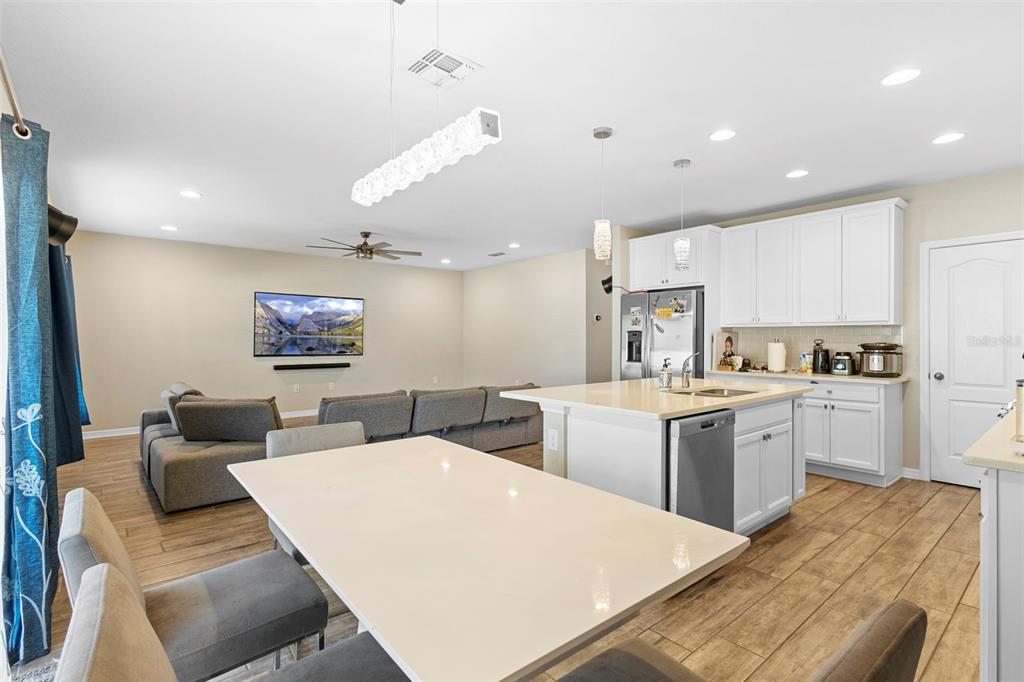 3937 Ceremony Cove Sanford, FL 32771 - Photo 7 of 51 a large room with kitchen island a stove a sink a dining table and chairs