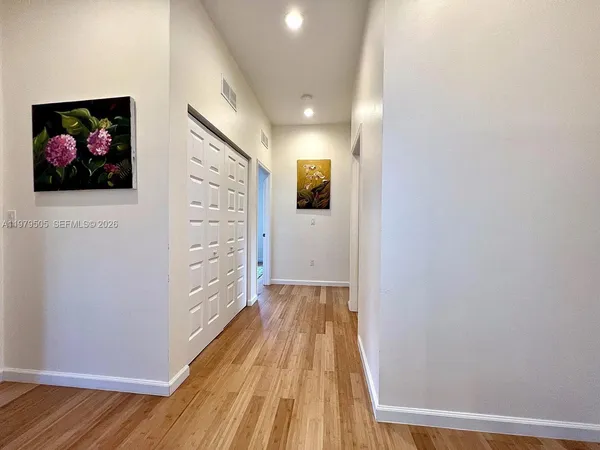 a view of a hallway with wooden floor and closet