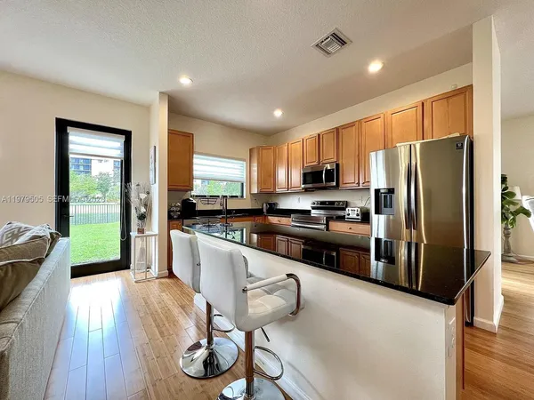 a kitchen with stainless steel appliances granite countertop a refrigerator a stove top oven a sink dishwasher and white cabinets with wooden floor