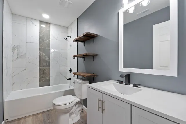 a bathroom with a sink toilet vanity and shower