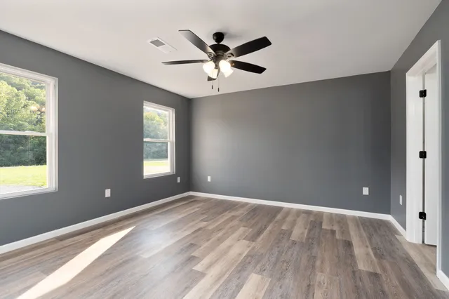 a view of an empty room with window and wooden floor