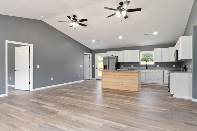 a large kitchen with cabinets appliances and a ceiling fan