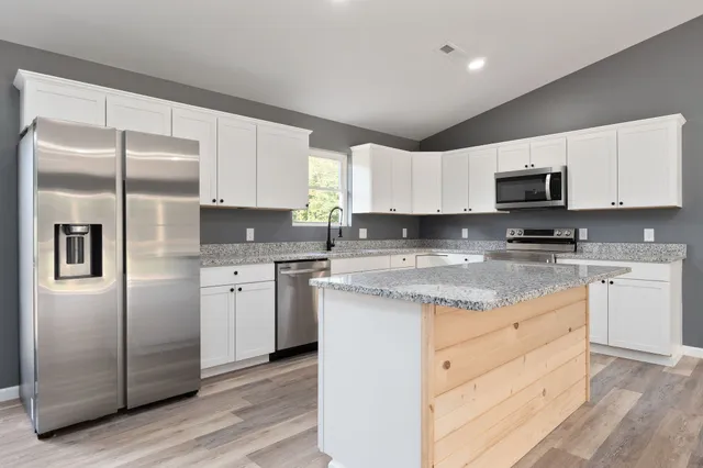 a kitchen with granite countertop white cabinets and stainless steel appliances