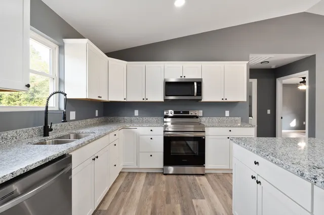 a kitchen with stainless steel appliances granite countertop a sink stove and microwave
