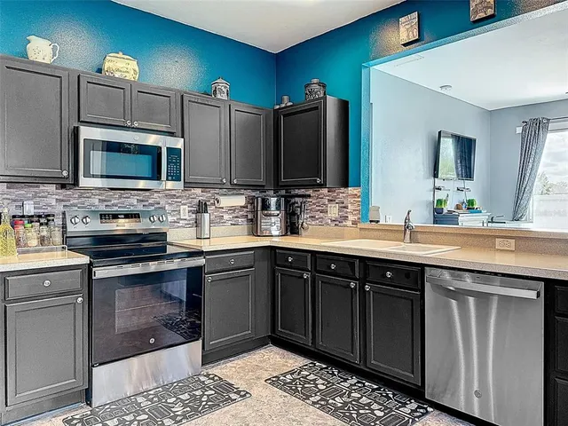 a large kitchen with stainless steel appliances kitchen island granite countertop a refrigerator and a stove top oven