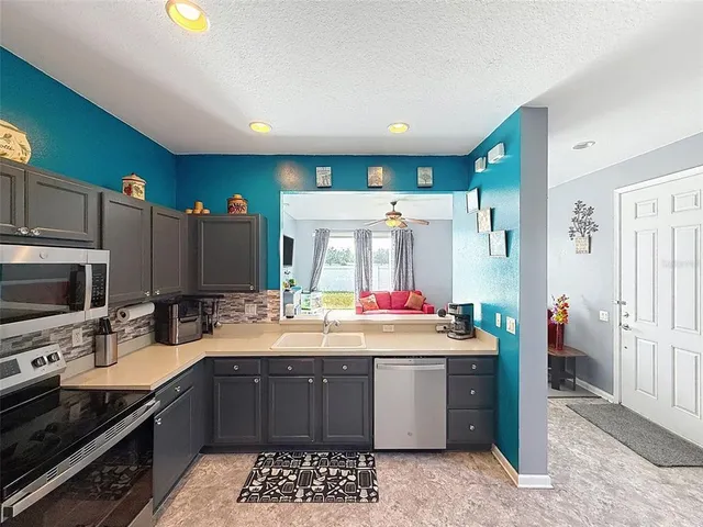 a kitchen with stainless steel appliances granite countertop a refrigerator a stove and a sink with wooden floors