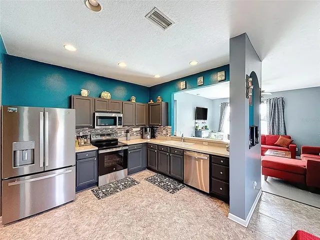 a kitchen with stainless steel appliances kitchen island granite countertop a refrigerator and a sink