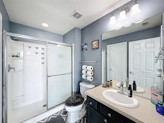 a spacious bedroom with a bed and a flat tv screen on the wall