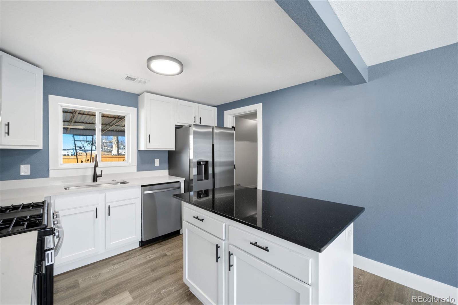 4933 Steele Street Denver, CO 80216 - Photo 12 of 31 a kitchen with stainless steel appliances granite countertop a sink stove and refrigerator